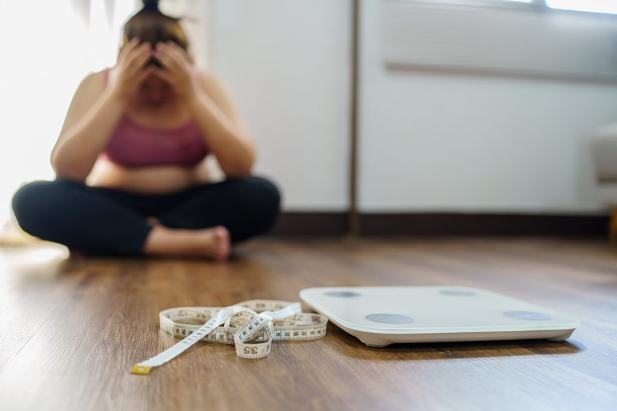 A woman sitting on the floor next to a scale and tape measure, associated with Revity Medical.